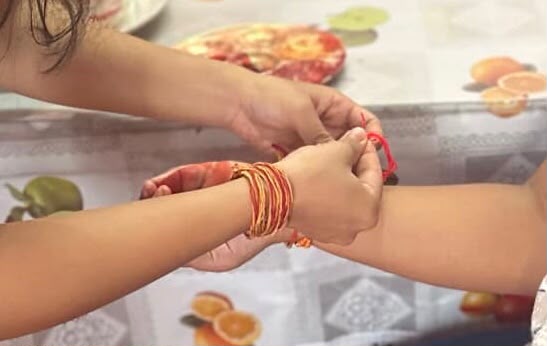 Rakhi being tied on a sibling’s wrist during Raksha Bandhan.