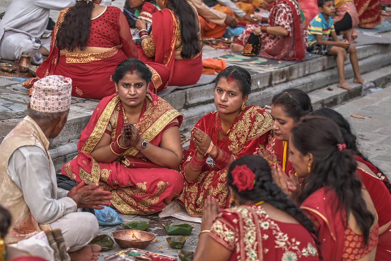 Women performing Rishi Panchami puja in traditional red attire


