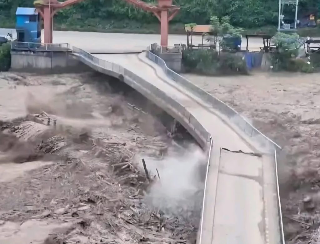 Floodwater damaging a concrete road and bridge
