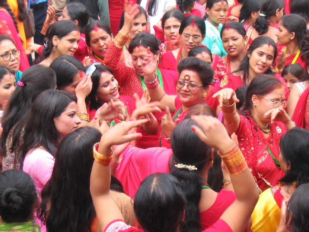 Nepali women in red traditional attire dancing and celebrating Teej festival