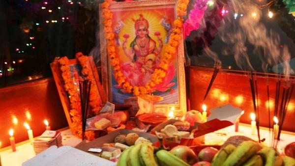 Kojagrat Purnima worship altar with Goddess Lakshmi image, oil lamps, incense sticks, flowers, and fruit offerings