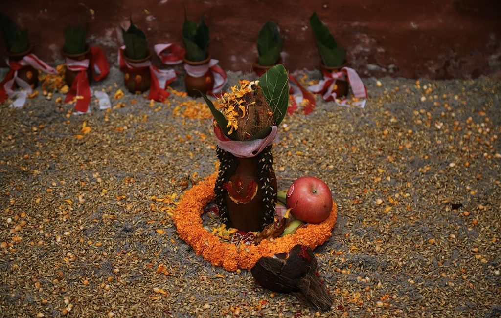 Ghatasthapana ritual kalash decorated with marigold flowers, coconut, green leaves, fruits, and traditional offerings.
